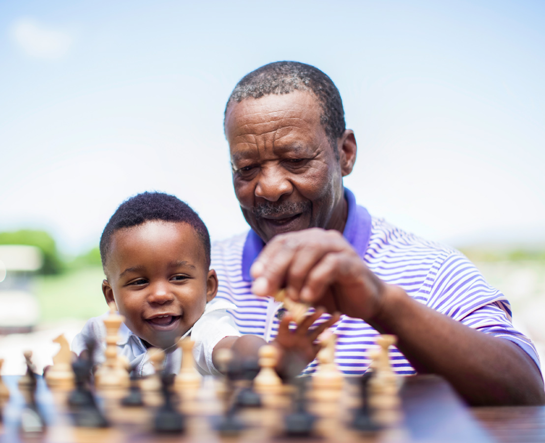 Un homme et un jeune enfant s’amusant avec un jeu d’échecs 