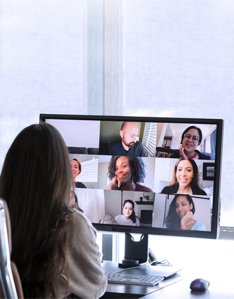 A person sits at a computer desk attending a virtual meeting